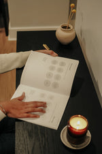 Load image into Gallery viewer, Woman opening Everyday Positive Workbook on desk with candle