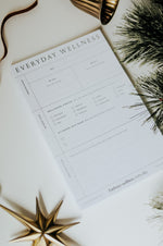 Load image into Gallery viewer, Everyday Wellness Notepad on white background with decorative elements