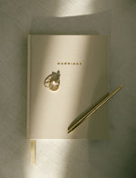 Load image into Gallery viewer, Marriage Journal, wedding rings, and gold pen on a light linen surface