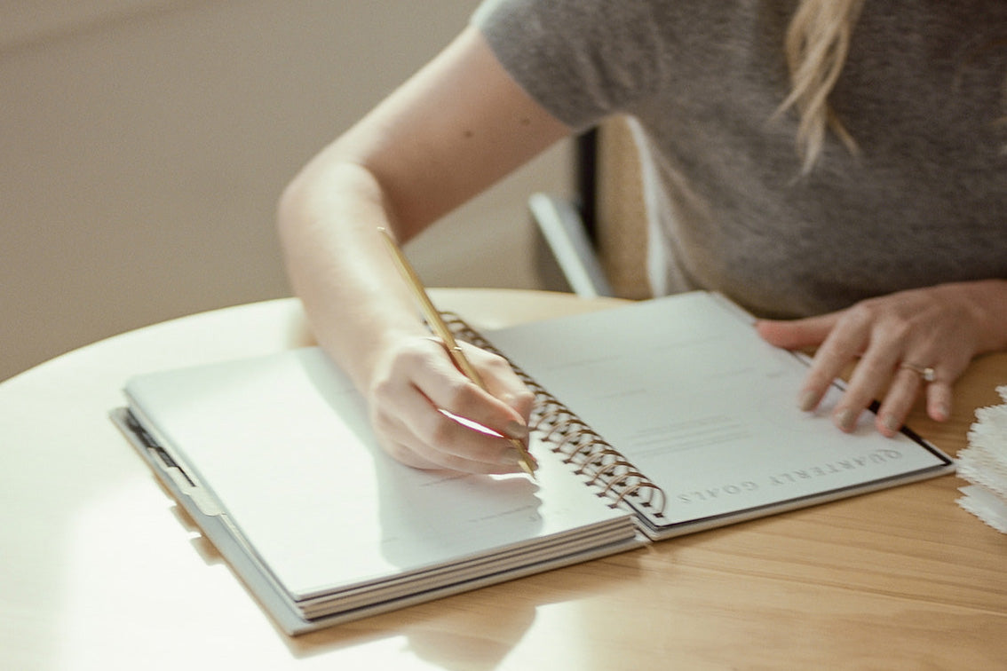 woman writing in a planner at desk