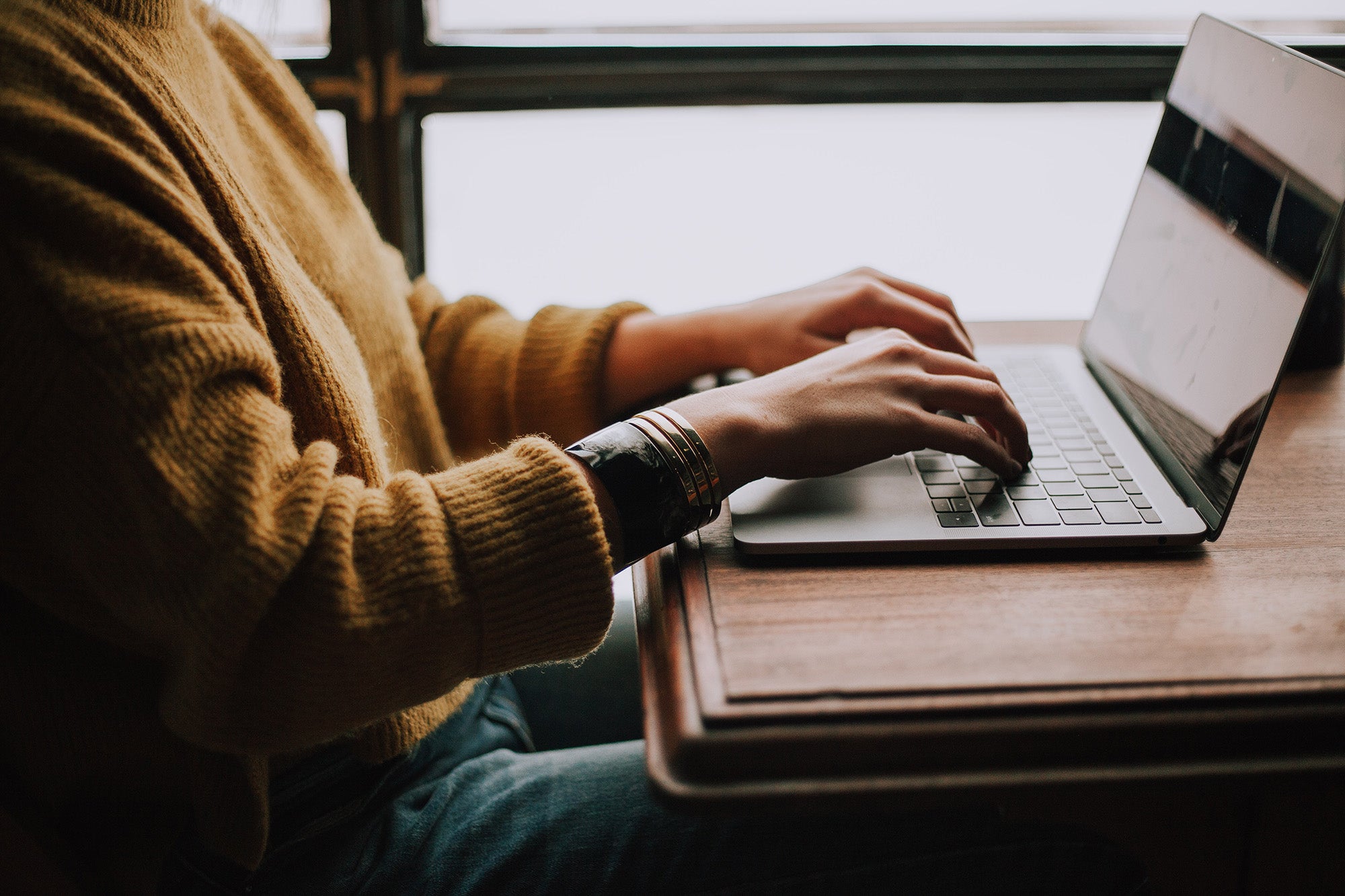 Young woman journaling on her laptop in a coffee shop