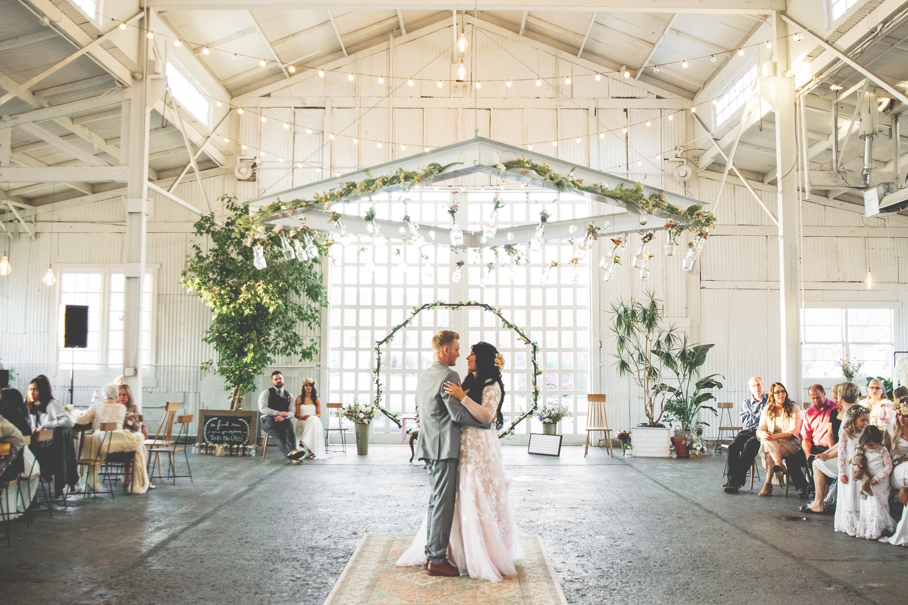 Urban, white, bright wedding venue with couple dancing in front of their wedding guests