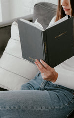 Load image into Gallery viewer, Engaged woman holding dark grey Engagement Journal on couch
