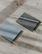 Load image into Gallery viewer, Slate blue and dark grey engagement journals with filtered light hitting the covers
