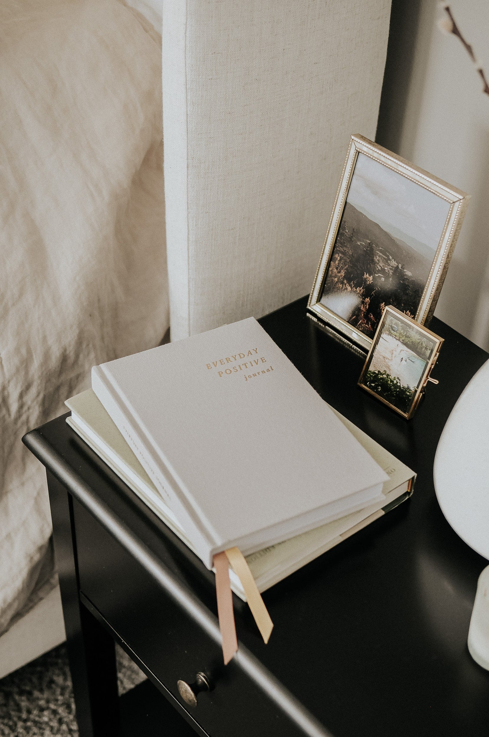 Everyday Positive Journal on nightstand with books and decor