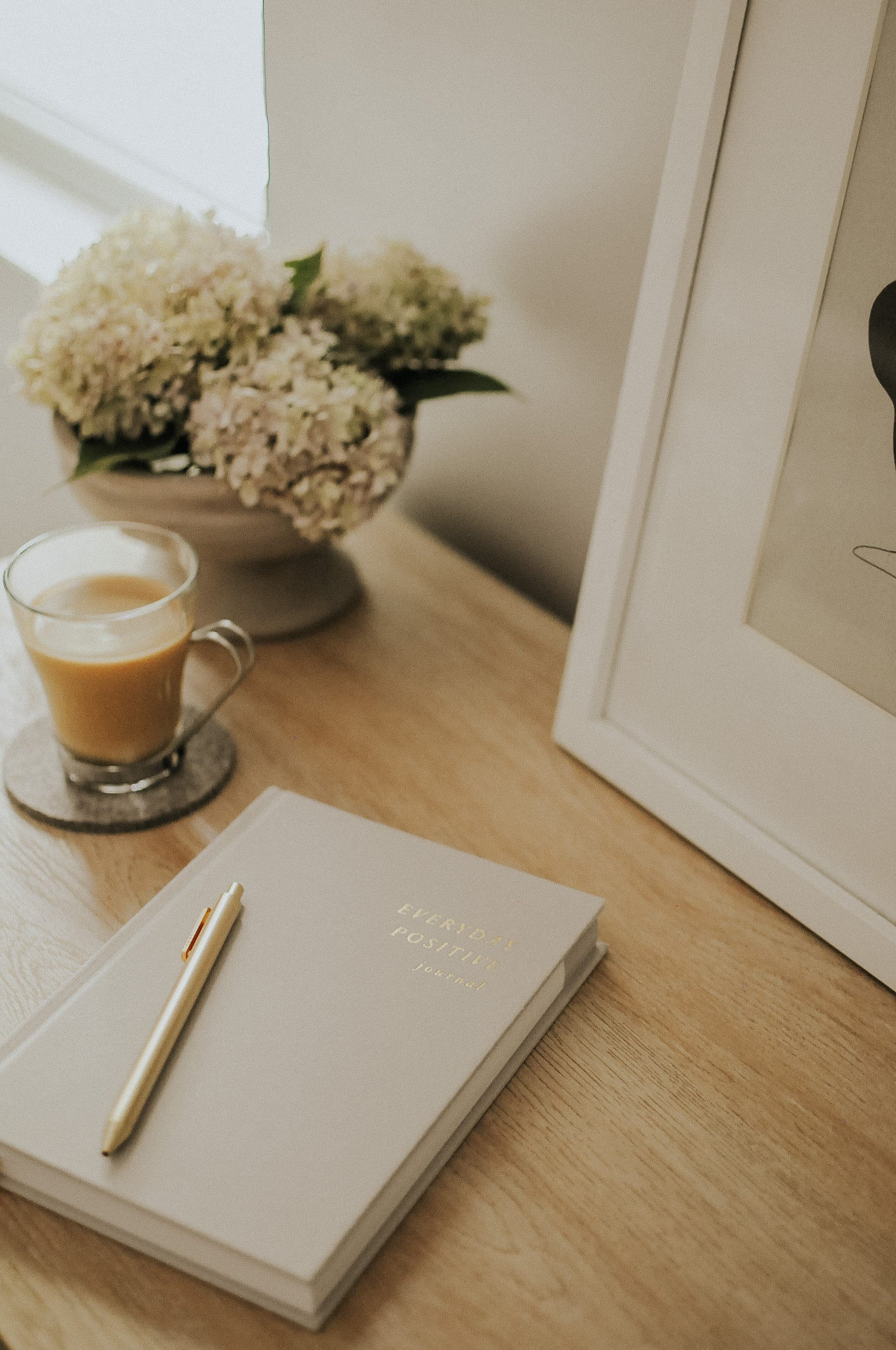 Everyday Positive Journal on desk with coffee and flowers