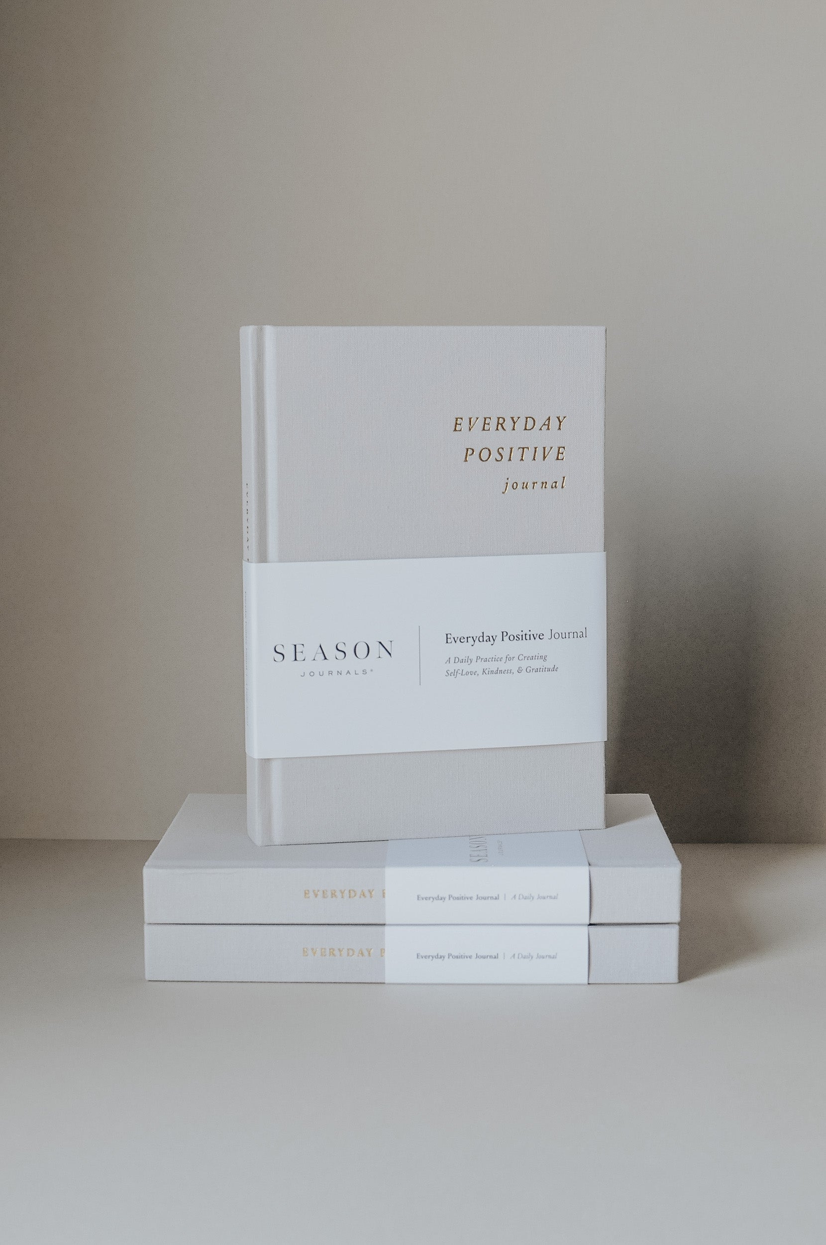 Stack of 'Everyday Positive' journals on a neutral background