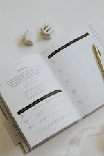 Load image into Gallery viewer, Open journal with pen and decorative items on a light surface
