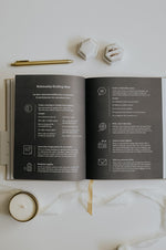 Load image into Gallery viewer, Open Marriage Journal with relationship-building ideas on a white surface with a candle and pen.
