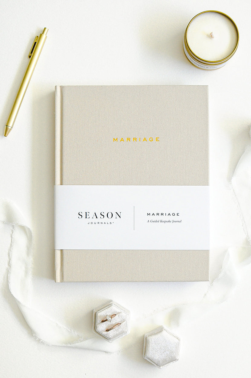 Marriage Journal on white background with candle, pen, and rings