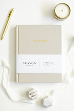 Load image into Gallery viewer, Marriage Journal on white background with candle, pen, and rings
