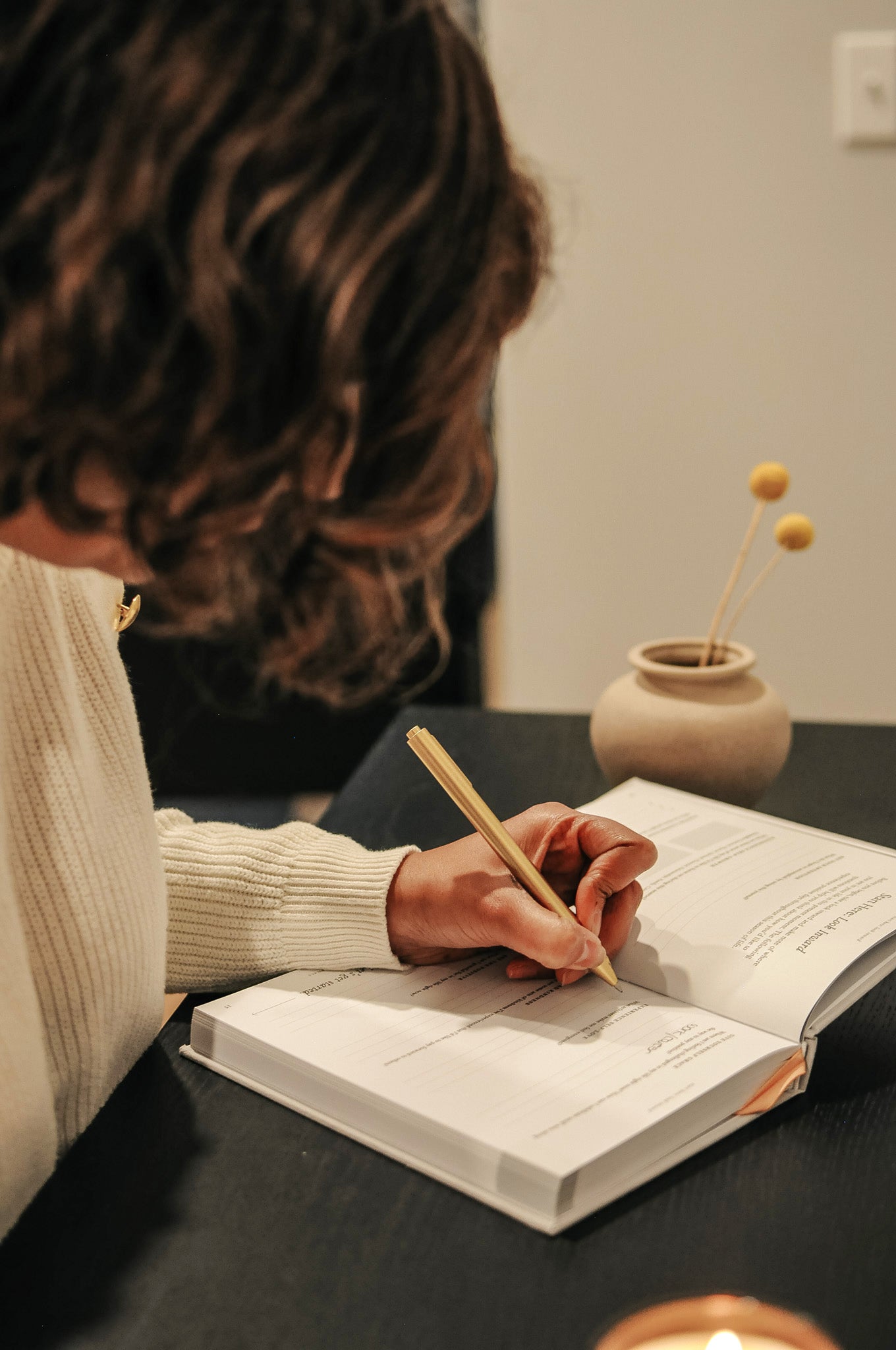 Woman journaling in Everyday Positive Journal on desk with candle