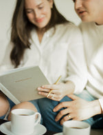 Load image into Gallery viewer, Smiling couple journaling together in the Pregnancy Journal with coffee in the foreground
